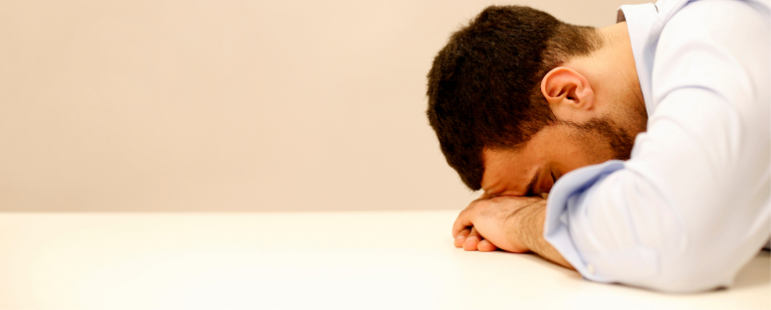 Man sad at failure rests head on desk